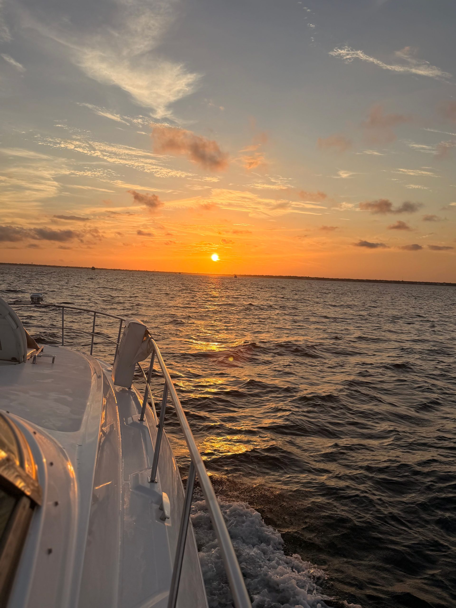 Golden sunset over Destin waters beside the Miss B Haven railing